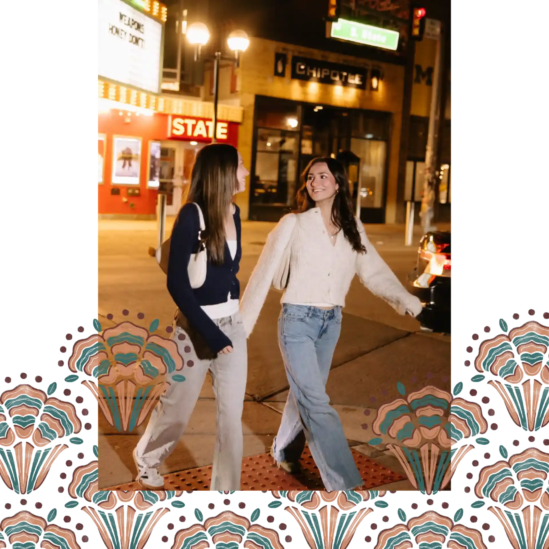 Two young women walk hand-in-hand at night on a city street near Ann Arbor Student Apartments, smiling at each other. They wear casual outfits with jeans and sweaters. Streetlights, theater signs, and cars glow above decorative floral patterns below.