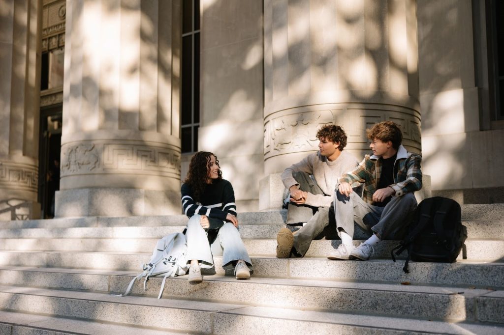 A group of University of Michigan students talking on the stairs leading to the Angell Hall building. 