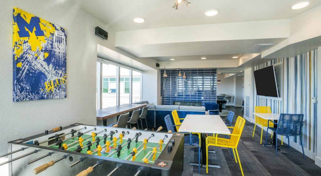 Sterling Arbor BLU student housing lounge with foosball table, study seating, blue tile fireplace and University of Michigan decor in Ann Arbor apartment community.