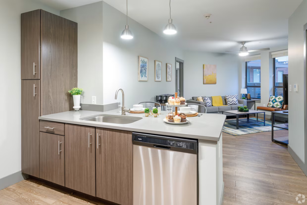 The Yard Ann Arbor student apartment interior features a modern kitchen with stainless steel appliances, quartz countertops and open-concept living room near the University of Michigan. 