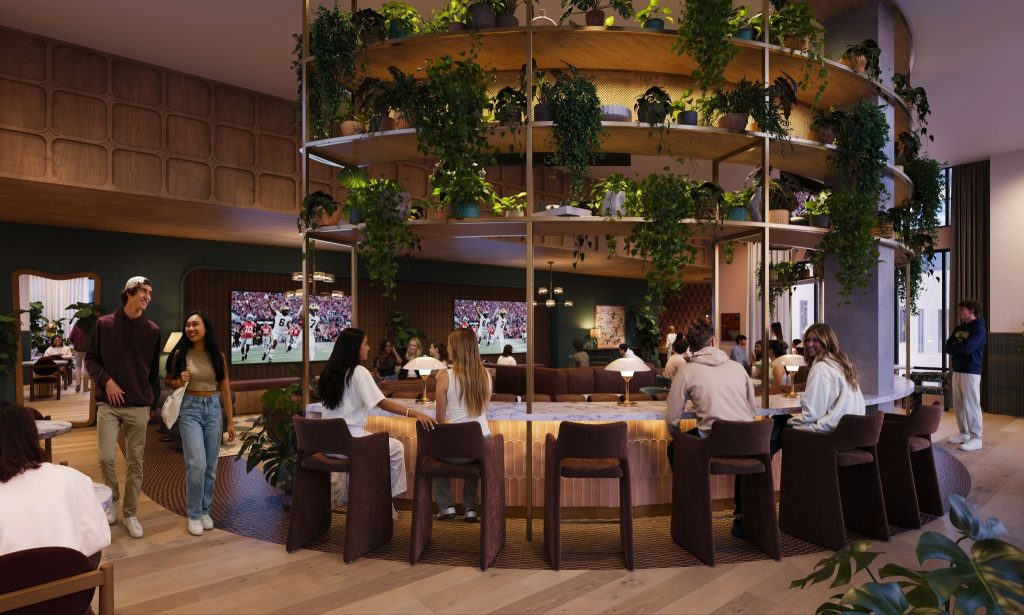 Rambler Ann Arbor club room with circular bar seating, indoor greenery feature, large TVs and social lounge space for University of Michigan student housing near campus.