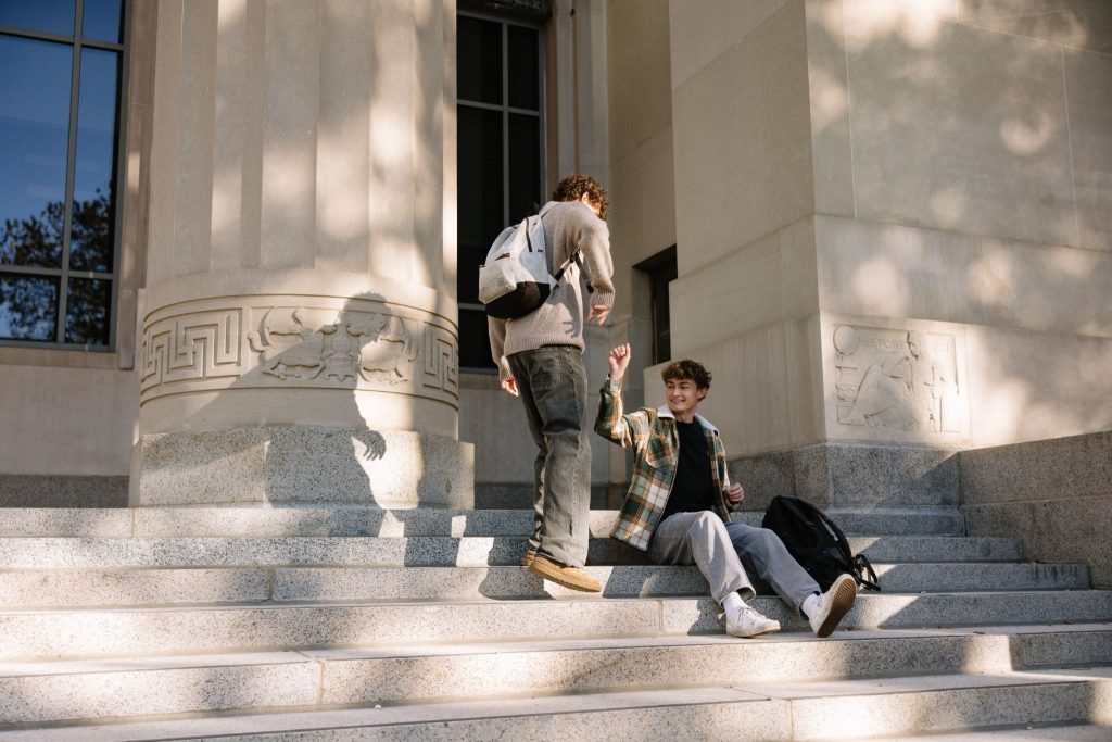 Two UMich students meeting each other on the steps of Angell Hall, an academic building on central campus.