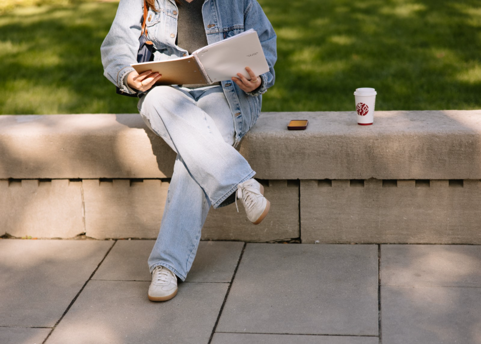 University of Michigan student sitting with their notebook on campus in Ann Arbor.