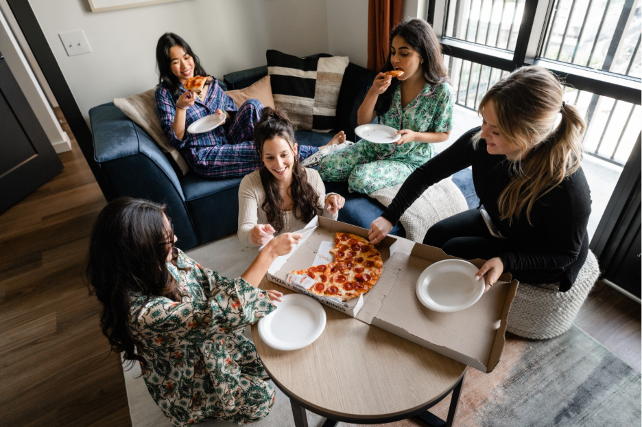 University of Michigan students eat pizza in their student apartment living room in Ann Arbor.