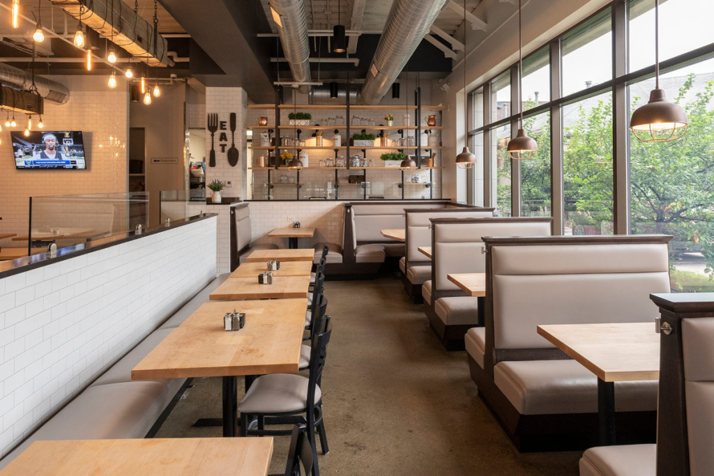 Interior of The Jagged Fork in Ann Arbor featuring modern booths, wooden tables and bright natural light, a well-known restaurant for brunch near the University of Michigan.