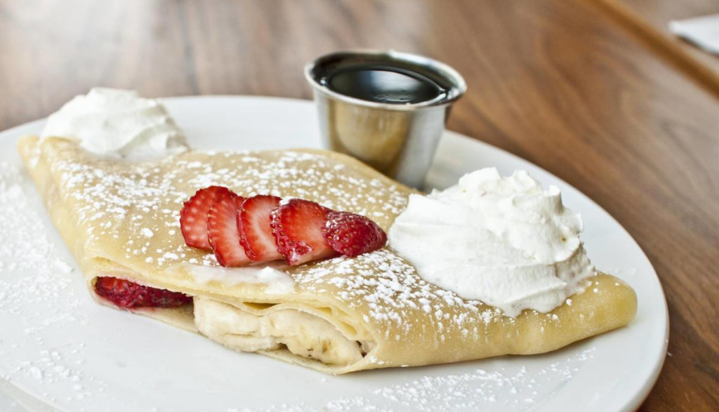 Strawberry and banana-filled crepe topped with whipped creme, a menu item at the brunch spot Café Zola.