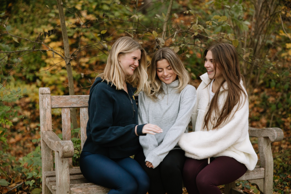 Three Umich students sitting on a bench in the Nichols Arboretum, a nature area located near the Hill on University of Michigan’s campus.