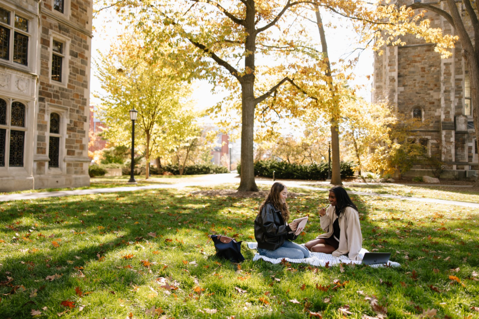 Two UMich students studying on the lawn in the Law Quad, located on Central Campus in Ann Arbor. 