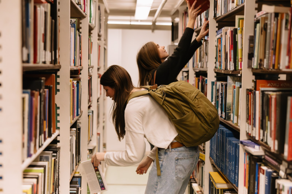 Two University of Michigan students looking through books at the Hatcher Graduate Library. 