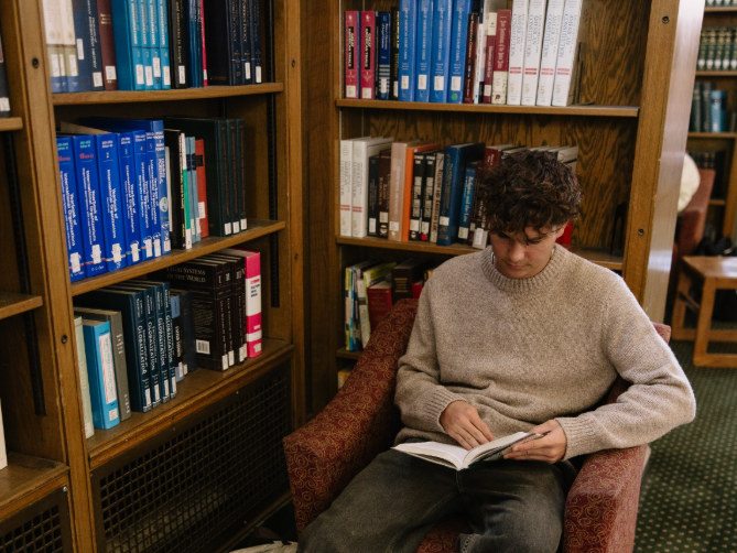 UMich student reading in the Hatcher Graduate Library by the Diag.