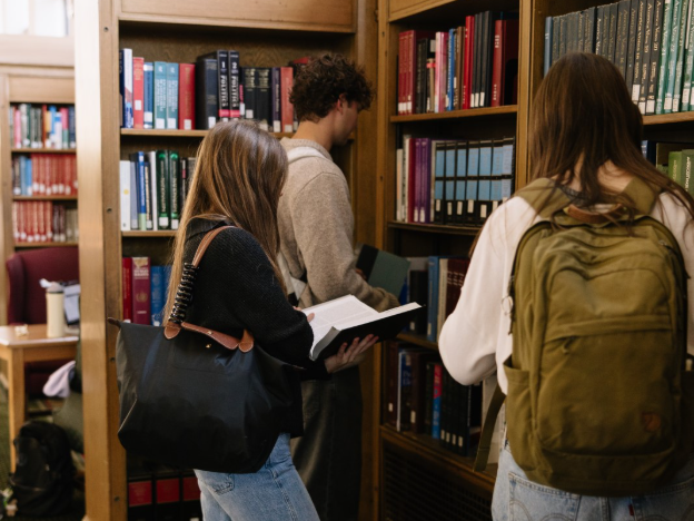 A group of UMich students looking through books at the Hatcher Graduate Library.  